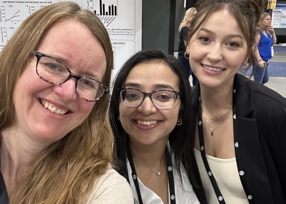 Josie Chanlder and two students at a conference standing in front of a research poster
