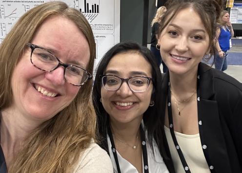 Josie Chanlder and two students at a conference standing in front of a research poster